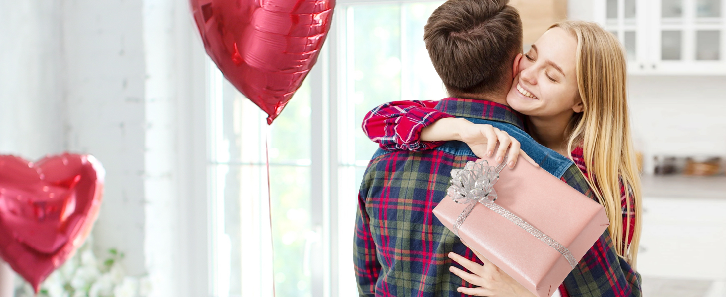 a couple holding a gift box and a heart shaped balloon.