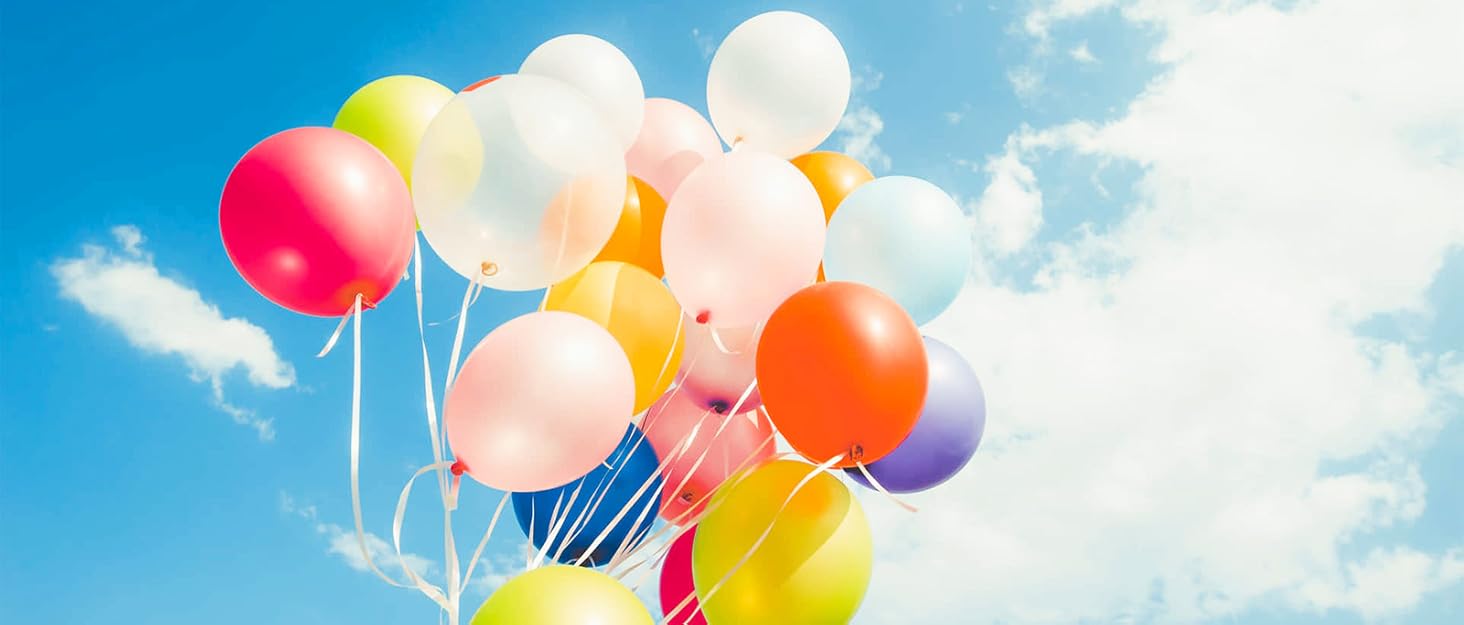 Colorful balloons floating against a bright blue sky with fluffy white clouds. Balloons include white, red, orange, yellow, and pink.