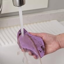 a hand rinsing the cooktop pad under running water in a sink