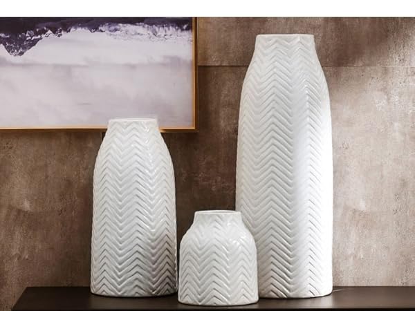 Three-piece corrugated white porcelain vases on a black table in front of the wall