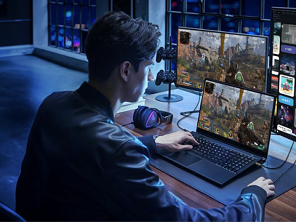 Person using multiple computer monitors in dark room, displaying game or graphics software on screens.