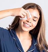 Woman smiling while wiping her face with a cleansing wipe.