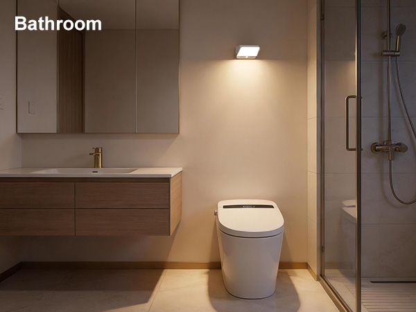 Text reads 'Bathroom'. Modern bathroom interior featuring wall-mounted vanity, elongated white toilet, recessed lighting, dark tile accents, and minimalist design.