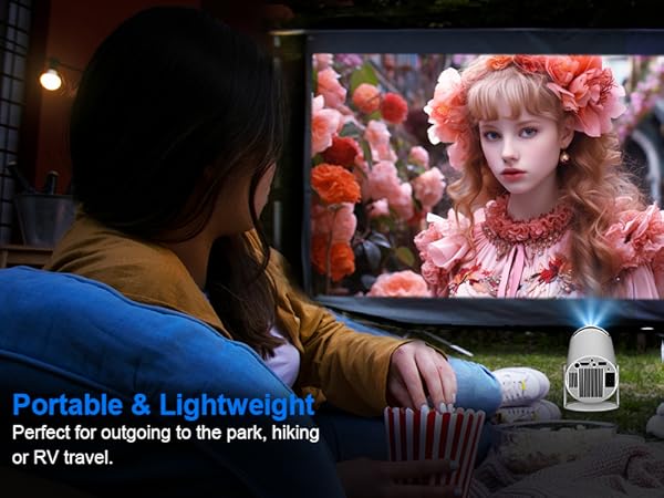 Portable projector setup showing movie screening in dark room with string lights, viewers seated watching large projected image.