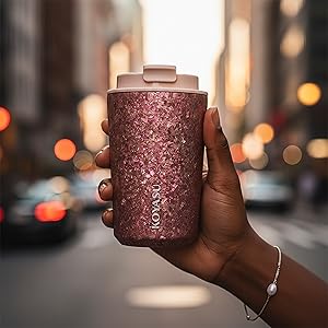 Hand holding KOYASU Ti-Zen Dawn Pink titanium mug. Crystallized texture, portable transit.