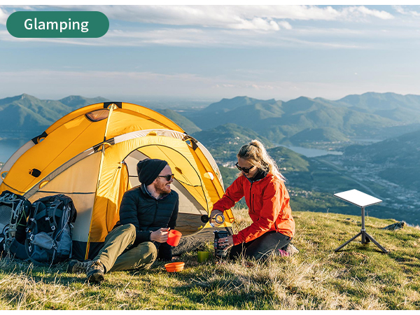 Text reads 'Glamping'. Yellow dome tent pitched on mountainside with two people sitting inside, mountains visible in background.