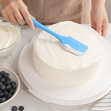 blue silicone spatula spreading cream on cake