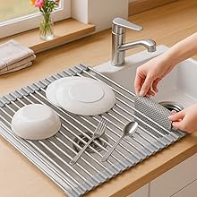 Plates and cups drying on roll-up silicone mat over sink