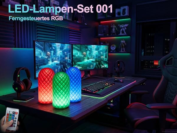 Text reads "LED-Lampen-Set 001" and "Ferngesteuertes RGB". Two glowing RGB LED cylindrical lamps in red and green on desk with gaming setup, monitors, and controller visible.