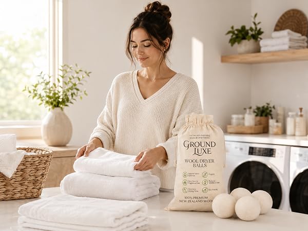 Woman folding soft towels with wool dryer balls in a bright laundry room