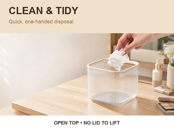 Hand placing a tissue into a clear open-top mini desktop trash can
