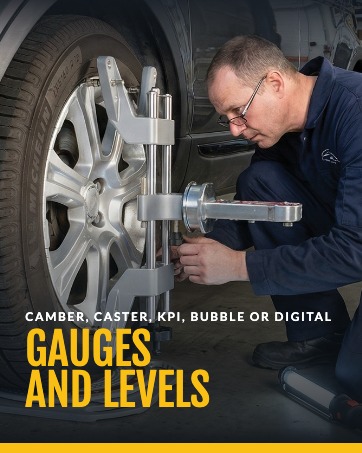 Gauges and levels. A mechanic reads the camber, caster, and KPI gauge on the wheel clamp