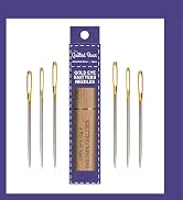 Text reads 'Gold Eye Kntters'. Multiple gold-plated sewing needles displayed alongside purple product packaging showing brand information.