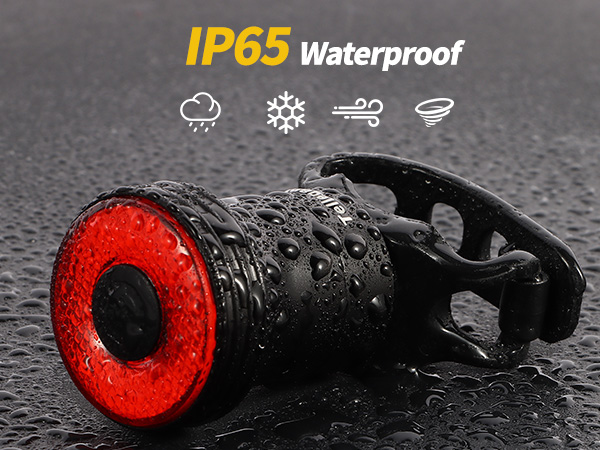 IP65 waterproof bicycle tail light with red LED ring. Black casing covered in water droplets. Icons show resistance to rain, snow, wind, and storms.