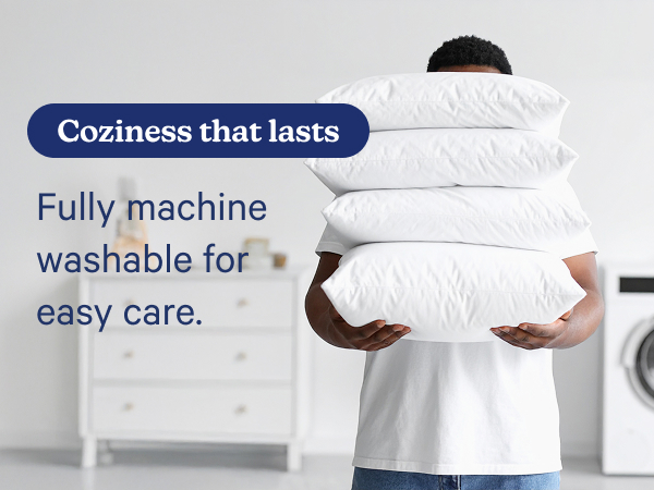 person holding stacked pillows with washing machine in background