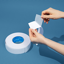 A pair of hands peeling the backing off our frosted non-skid tape on a blue background