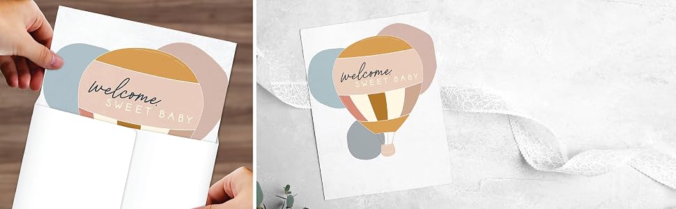 A giant baby shower folded greeting card on a table and also in a jumbo white envelope.