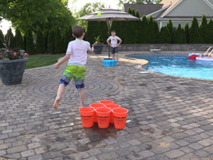 two kids playing bucketball by the pool