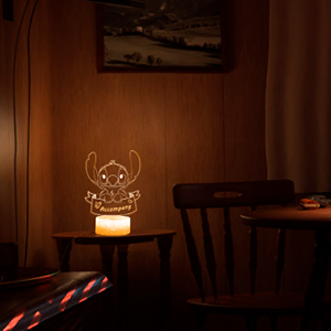 Dimly lit room with a glowing deer-shaped light fixture on a table, casting warm ambient light. Wooden chair visible in background.