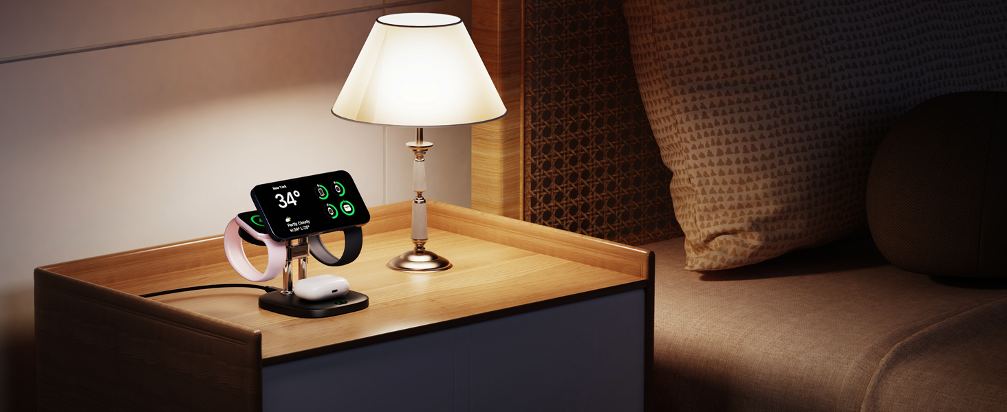Bedside table with lamp, digital alarm clock displaying time and temperature, and a smartphone in a charging dock.