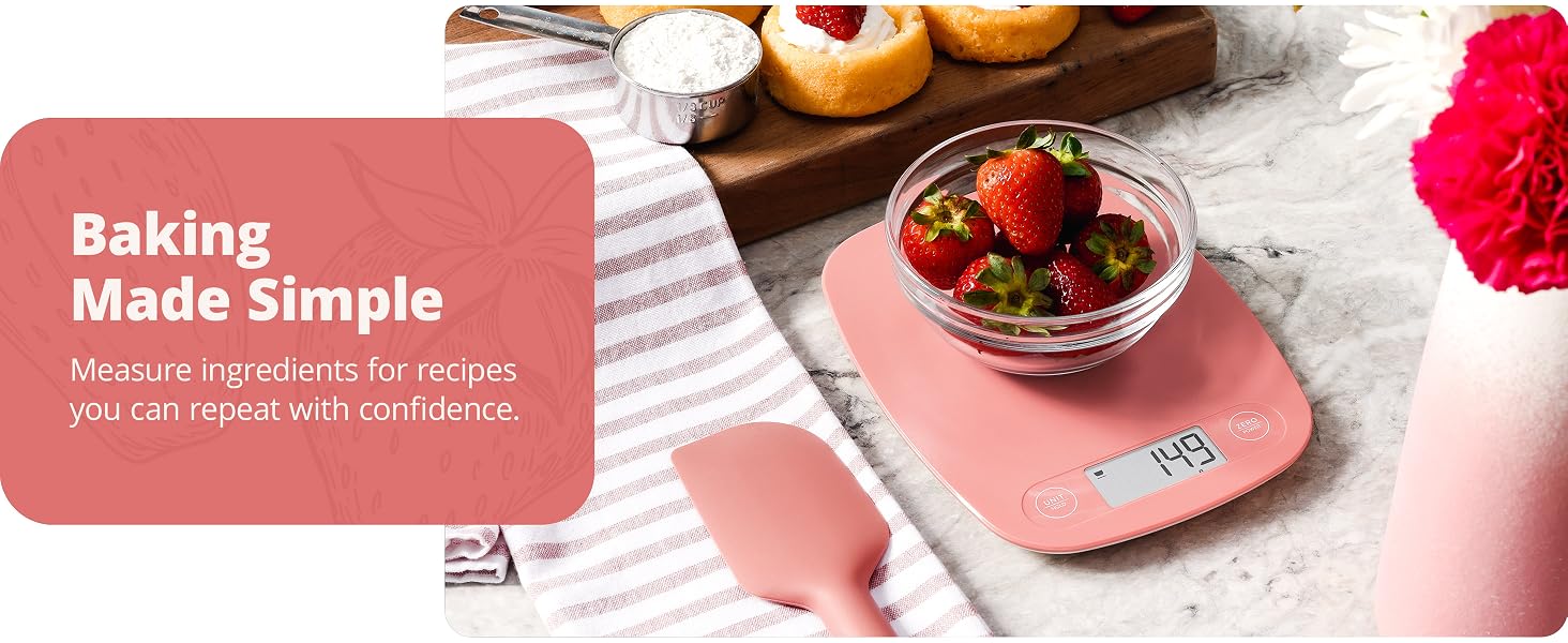 greater goods coral pink kitchen scale on marble counter weighing bowl of strawberries