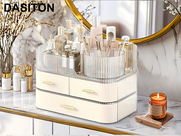 Cream-colored cosmetic organizer with clear acrylic top compartments and drawers. Features gold handles and ribbed texture. Holds makeup brushes and various beauty products on a marble surface.