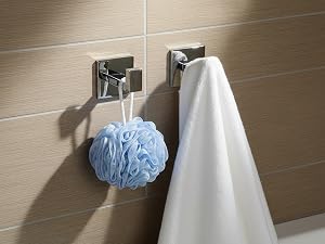 Bathroom accessories mounted on beige tiled wall, including soap dispenser and blue loofah or washing sponge.