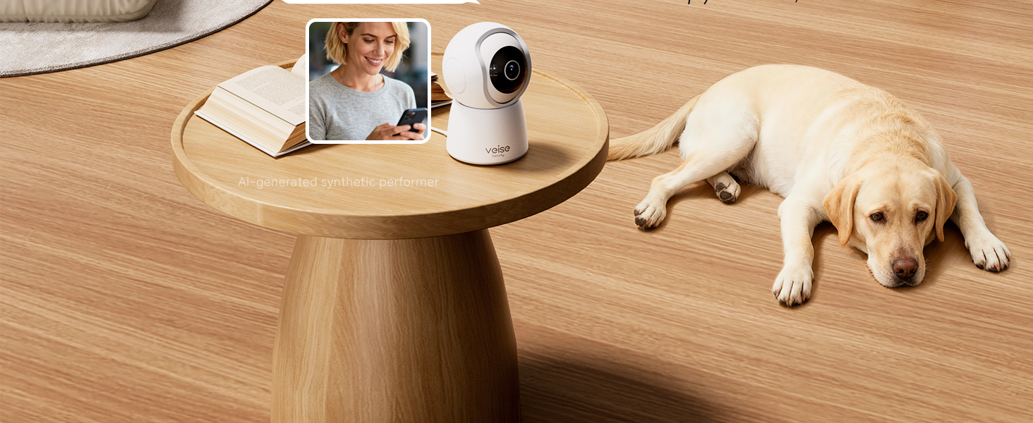 indoor pet camera on a wooden side table in a living room, with a Labrador resting on the floor