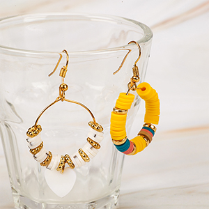 Hand-made earrings hanging on a glass.