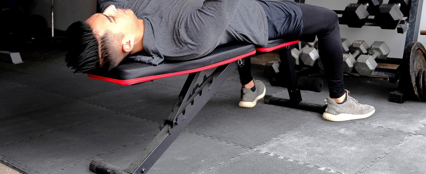 man doing bench press in home gym with weights and exercise mat gym flooring