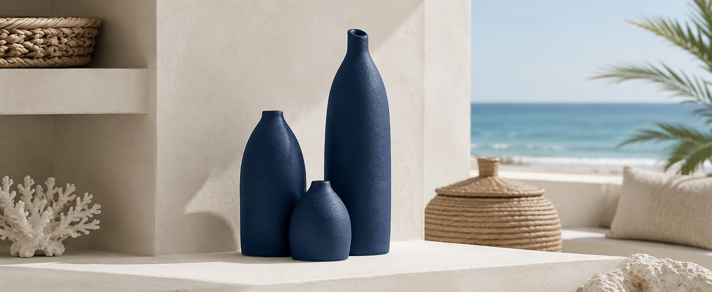 Three-piece navy blue textured vase set on a coastal shelf with woven decor and sea view.