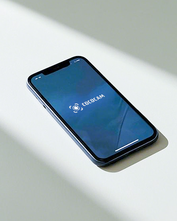 Smartphone displaying blue screen with app interface, photographed on white surface with dramatic shadow.