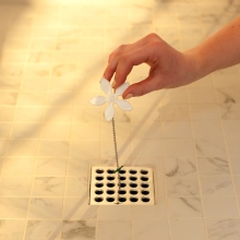 Hand installing DrainWig into a shower Drain
