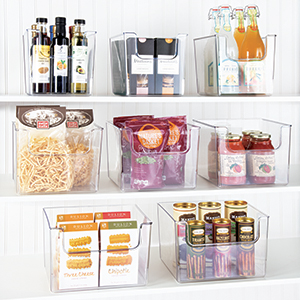 clear plastic bins holding bottles, jars, pasta, snacks on shelves, white pantry setting