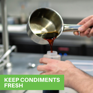 A person adding teriyaki sauce from a saucepan into a plastic squeeze bottle.