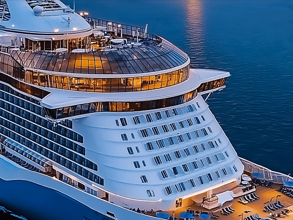 Series of photos showing a luxury cruise ship exterior at dusk, illuminated by warm lighting. Multiple decks and balconies visible against blue ocean background.