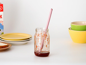 Long mini silicone spatula reaching the bottom of a jar to scrape sauce clean