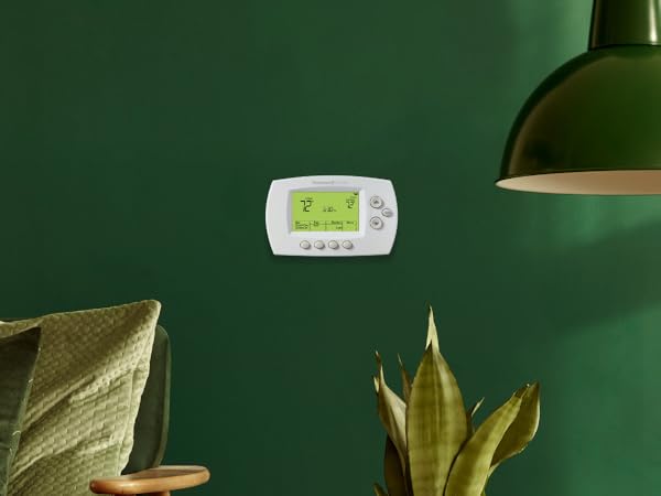 Wi-Fi 7-Day Programmable Thermostat on a green wall