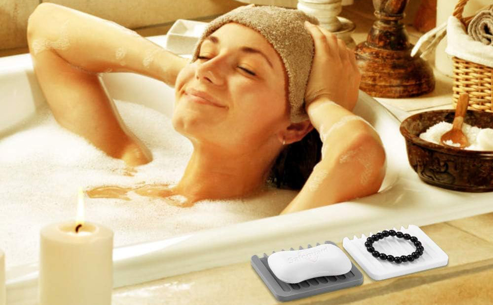 A lady enjoys a bubble bath. Silicone trays hold soap and small accessories on the tub ledge.