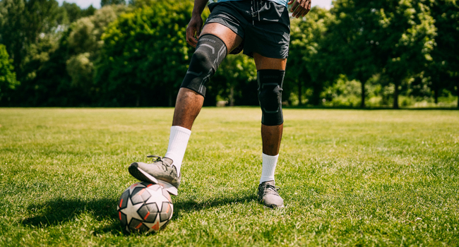 Man kicking a soccer ball on a field wearing BODYPROX