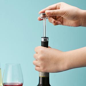a hand holding a wine bottle with a corkscrew.