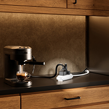 Maximm flat extension cord powering a kitchen countertop espresso machine.