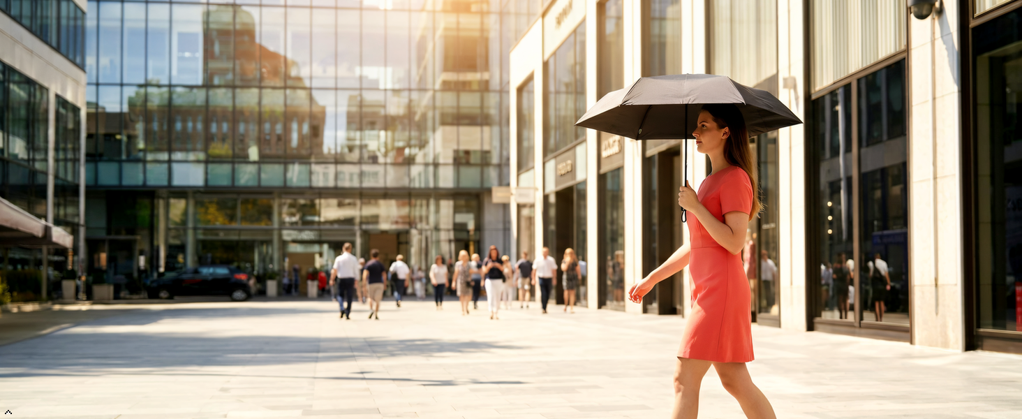 Woman in red dress with black compact umbrella walking in modern urban plaza setting