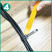 Cable organizer being attached to bundled wires. A yellow plastic tool is inserting a black zip tie around the cables on a wooden surface.