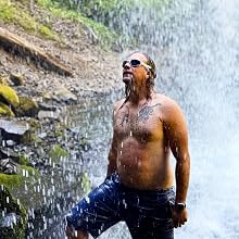 A man standing under a waterfall looking up