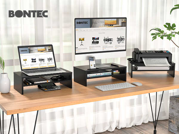 Three black monitor stands on a wooden desk. Each stand has a shelf for devices. Laptop, desktop monitor, and printer visible on stands.