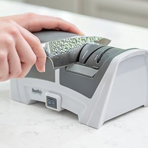 kitchen knife being sharpening in handheld electric knife sharpener manual sharpening