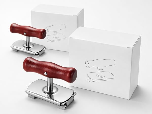 close view of two white paper boxes and red-brown wood handle jar openers