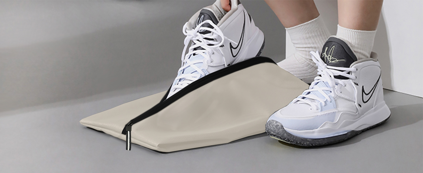 Athletic footwear positioned on a beige folding or collapsible shoe cover mechanism with black trim.