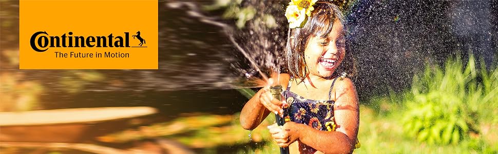 Little girl splashing herself in her backyard with water from a Continental water hose